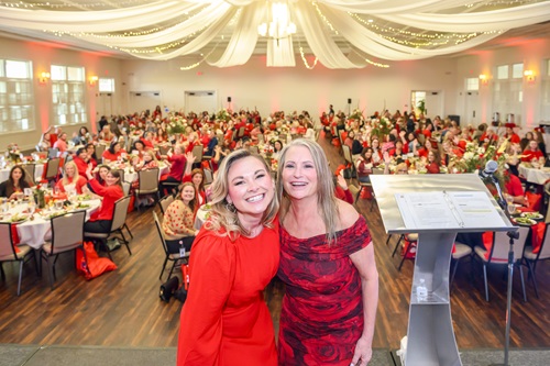 Two women dressed in red taking a selfie on stage.